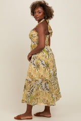 woman wearing a yellow tropical print halter maxi dress with a tie-back detail and flowing skirt