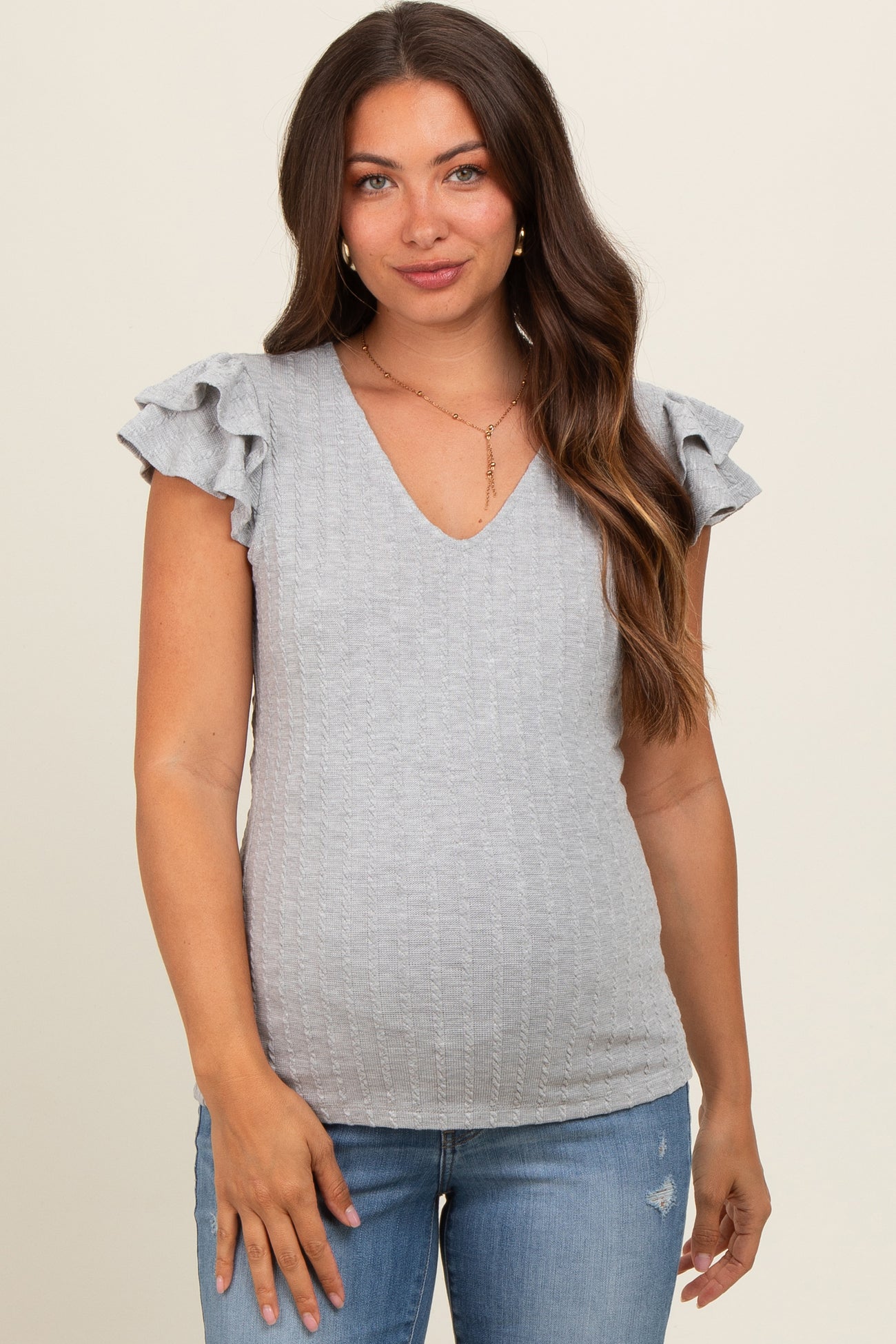 woman wearing a light gray maternity top with ruffle sleeves and a v-neckline