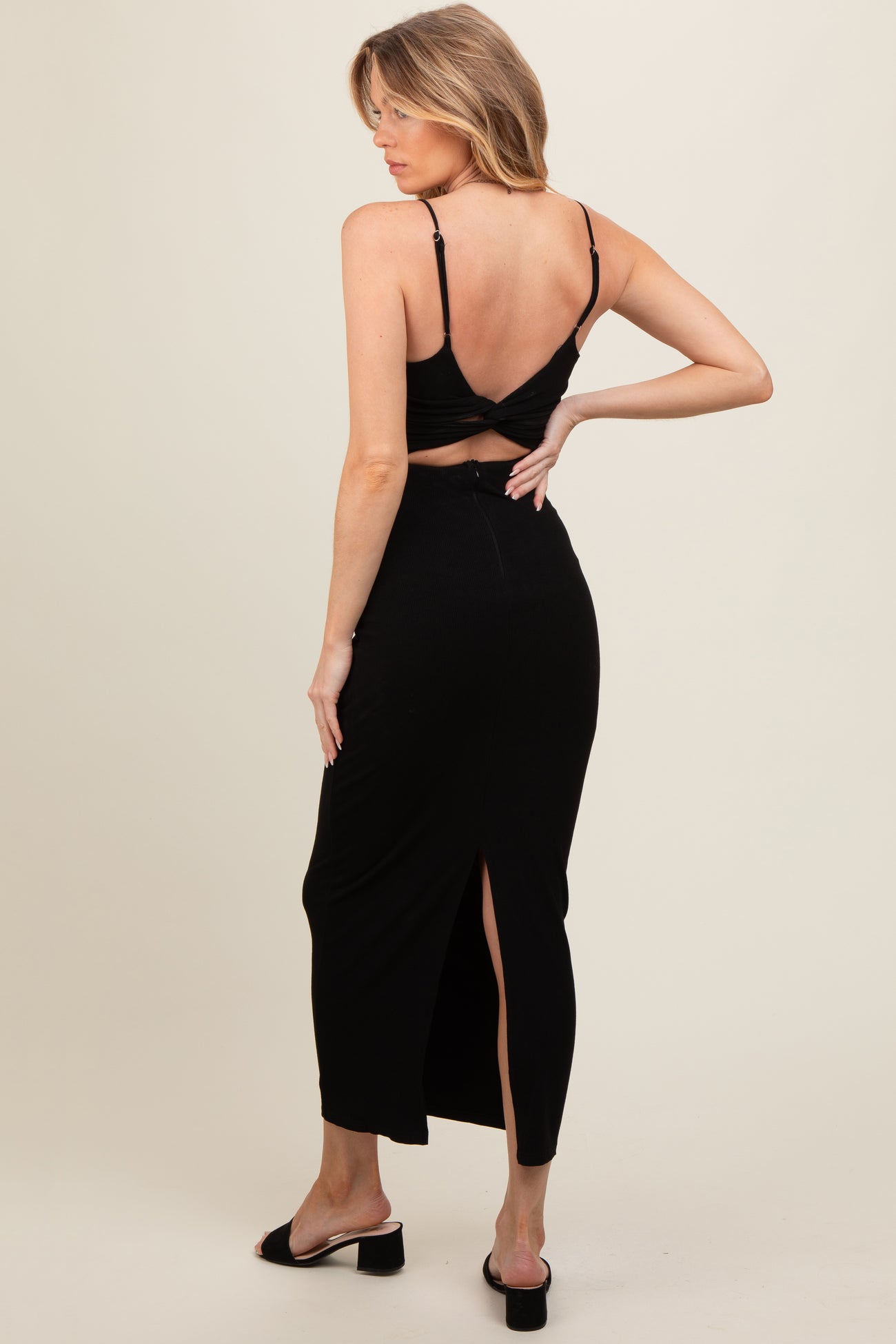 woman wearing a black maternity two-piece set with a cropped top and a long skirt featuring a side slit