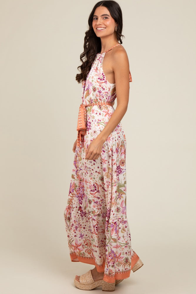 woman wearing a floral maxi dress with a halter neck and orange accents, styled with platform sandals