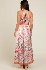 woman wearing a floral maxi dress with a back tie detail and a flowy skirt in pink and cream tones