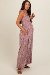 woman wearing a floral maternity maxi dress in mauve with a tie strap and pockets, showcasing her baby bump