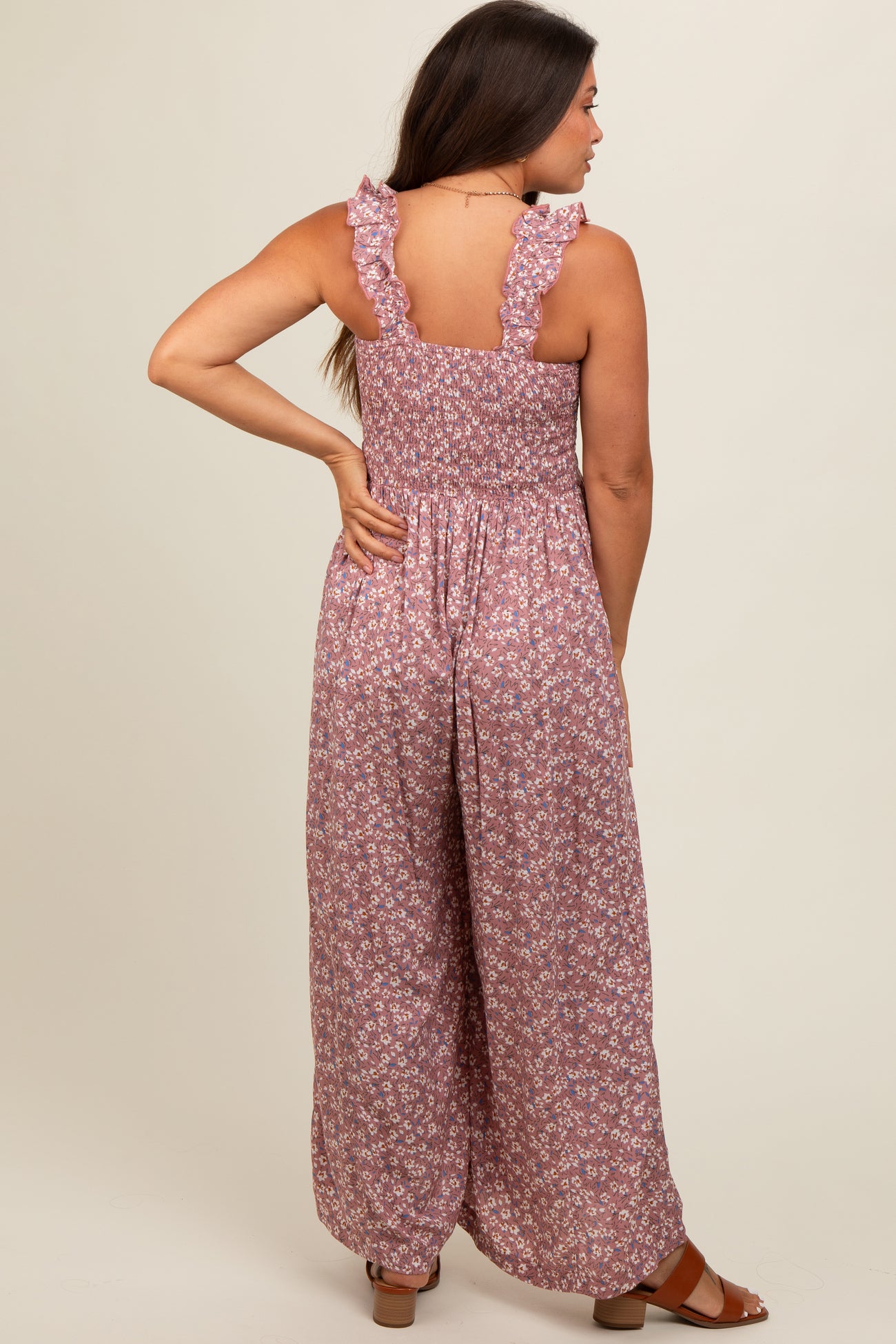 woman wearing a floral print maternity jumpsuit with ruffled straps and a smocked back, showing no baby bump