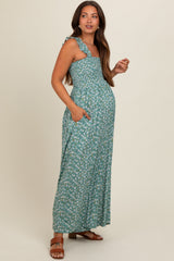 woman wearing a green floral print maternity maxi dress with ruffled straps and pockets, showing her baby bump