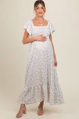 woman wearing a light floral print maternity maxi dress with short flutter sleeves and a visible baby bump