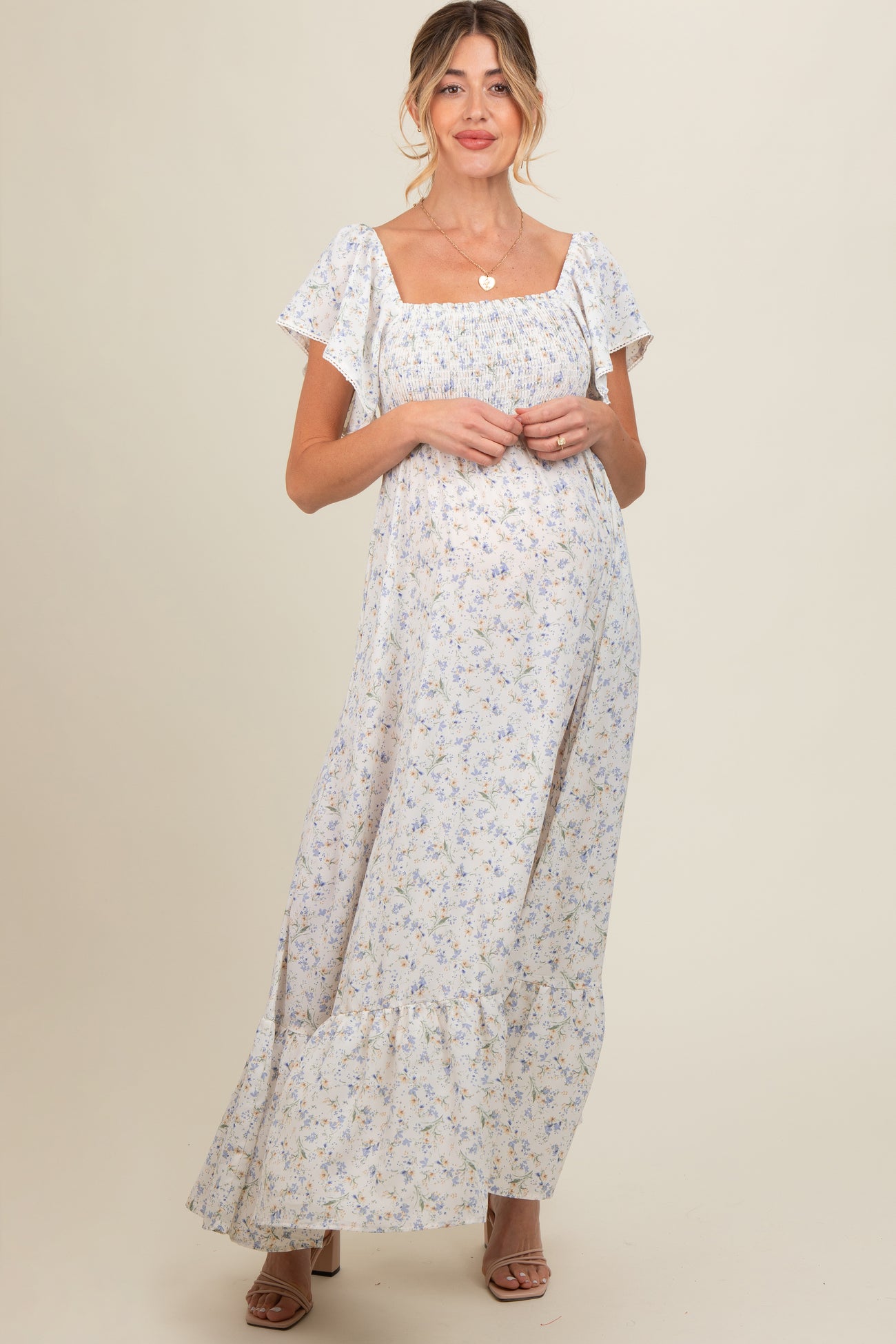 woman wearing a white floral print maternity maxi dress with short sleeves and a square neckline, showing her baby bump