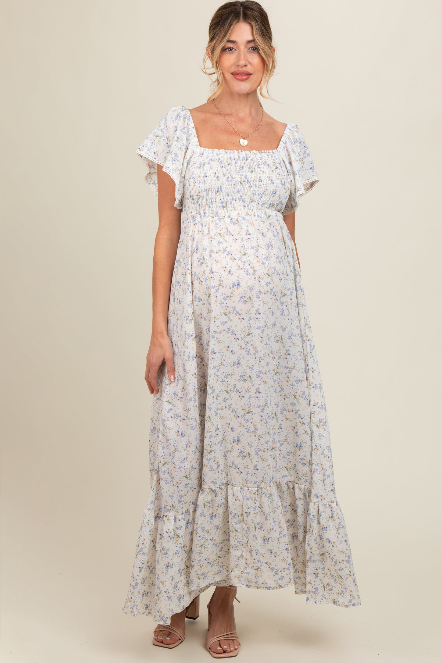 woman wearing a light blue floral maternity maxi dress with ruffled sleeves and a visible baby bump