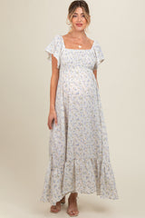 woman wearing a light blue floral maternity maxi dress with ruffled sleeves and a visible baby bump