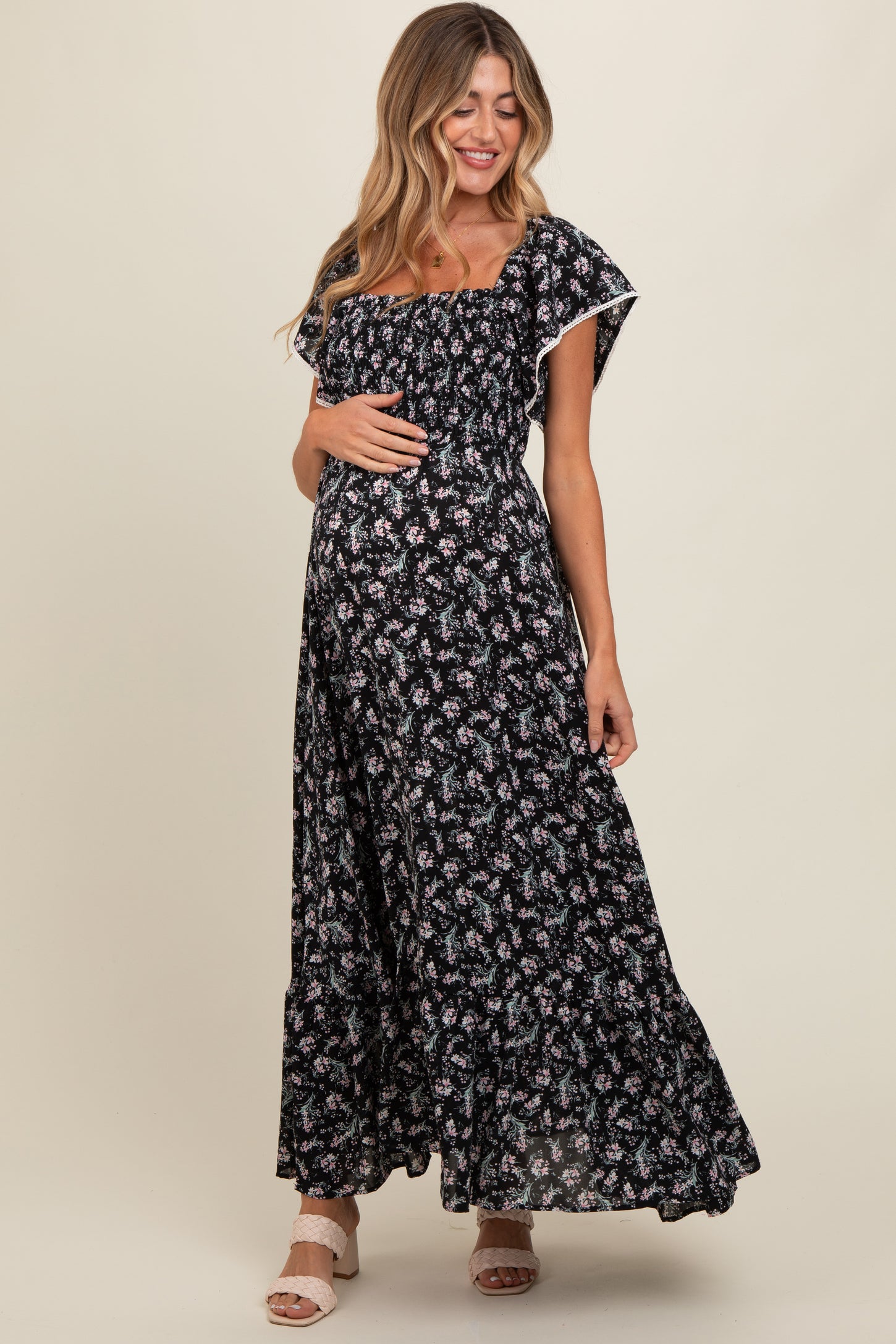 woman wearing a black floral maternity maxi dress with ruffle sleeves and a visible baby bump