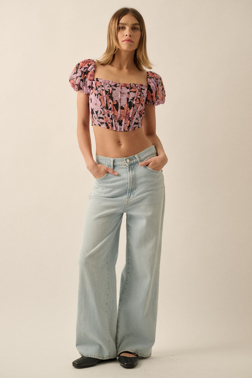 woman wearing a pink floral cropped top with puff sleeves and light blue wide-leg jeans