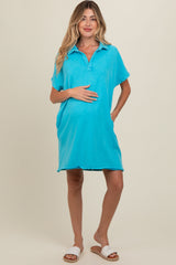 woman wearing a bright turquoise maternity polo dress and holding her baby bump