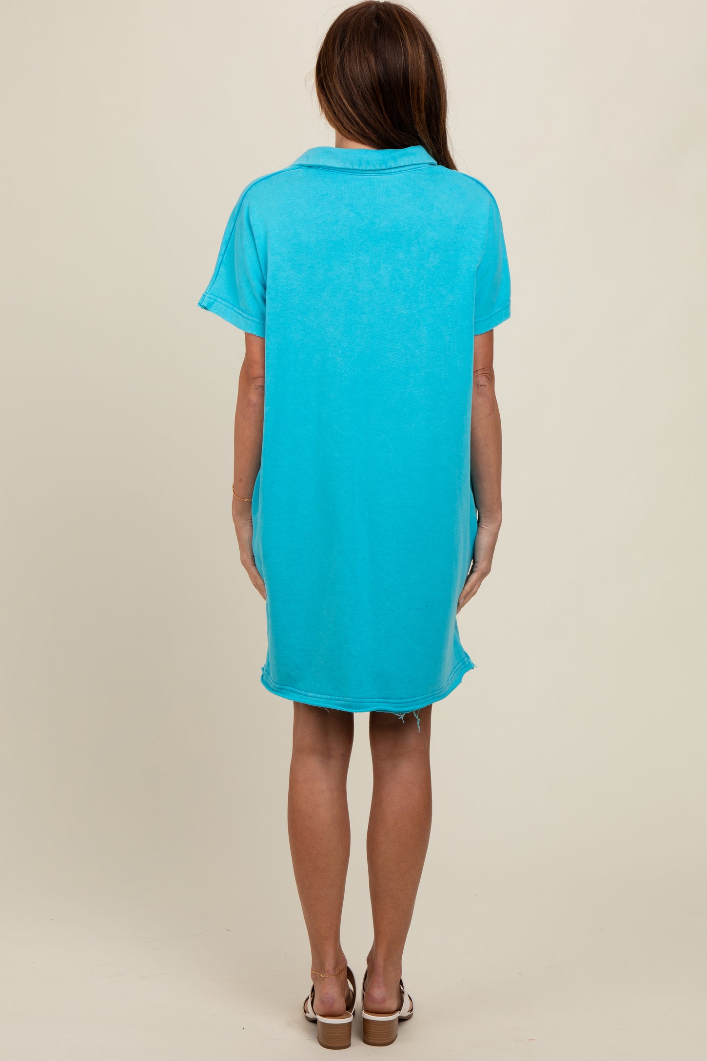 woman wearing a vibrant turquoise oversized short sleeve dress, showing the back view