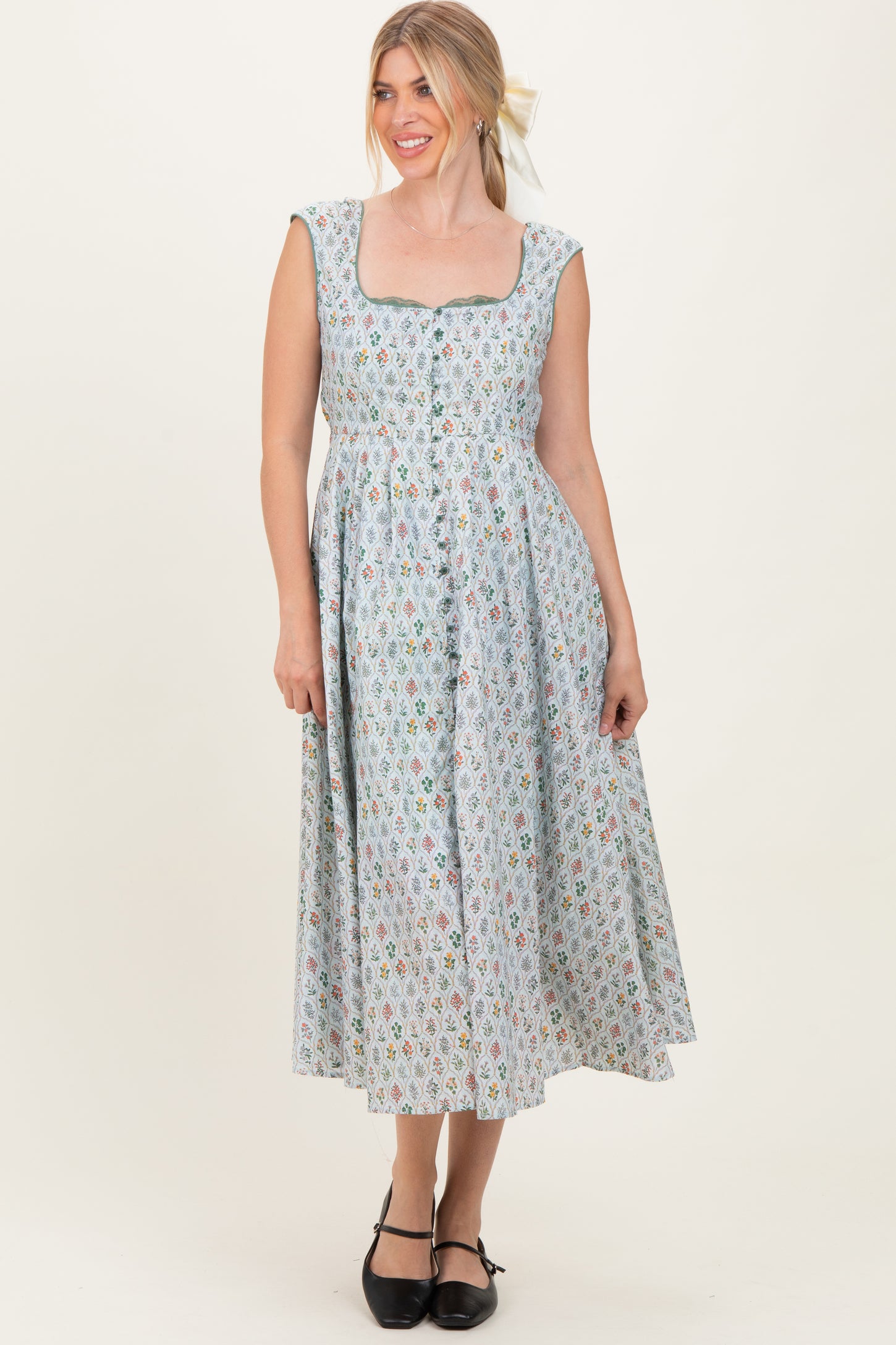 woman wearing a light blue floral midi dress with a square neckline and buttons down the front