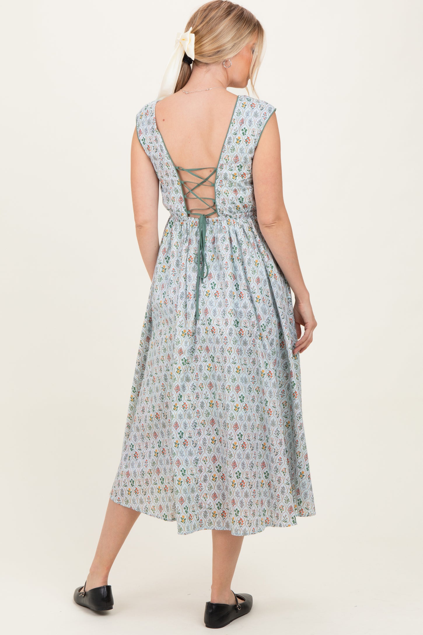 woman wearing a light blue floral backless midi dress with a lace-up detail