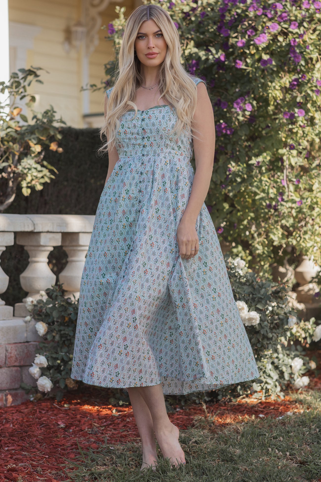 woman wearing a pastel floral print midi dress with a strapless design and flowing skirt, standing outdoors