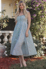woman wearing a pastel floral print midi dress with a strapless design and flowing skirt, standing outdoors