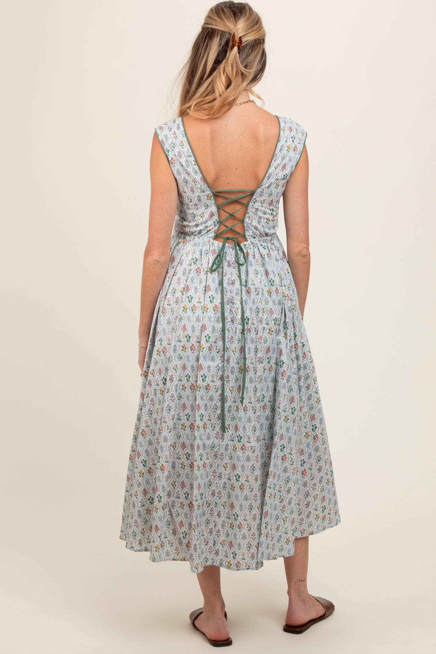 woman wearing a light blue floral maternity dress with a lace-up back and flowing skirt