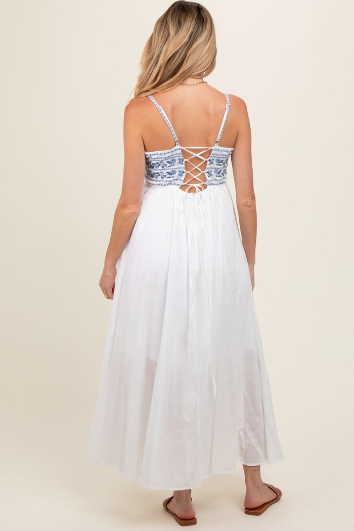 woman wearing a white maternity maxi dress with a blue patterned bodice and lace-up back detail
