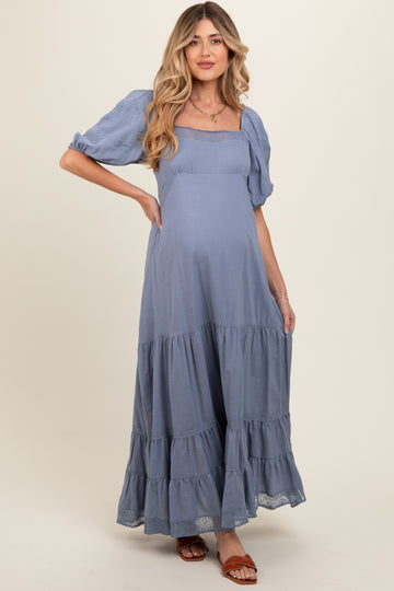 woman wearing a light blue tiered maternity dress with puff sleeves and a baby bump visible
