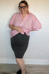 woman wearing a pink and white striped maternity shirt knotted at the waist and a black striped maternity skirt, showing baby bump