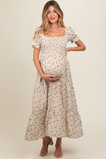 woman wearing a floral maternity dress with puff sleeves and tiered skirt, showing her baby bump