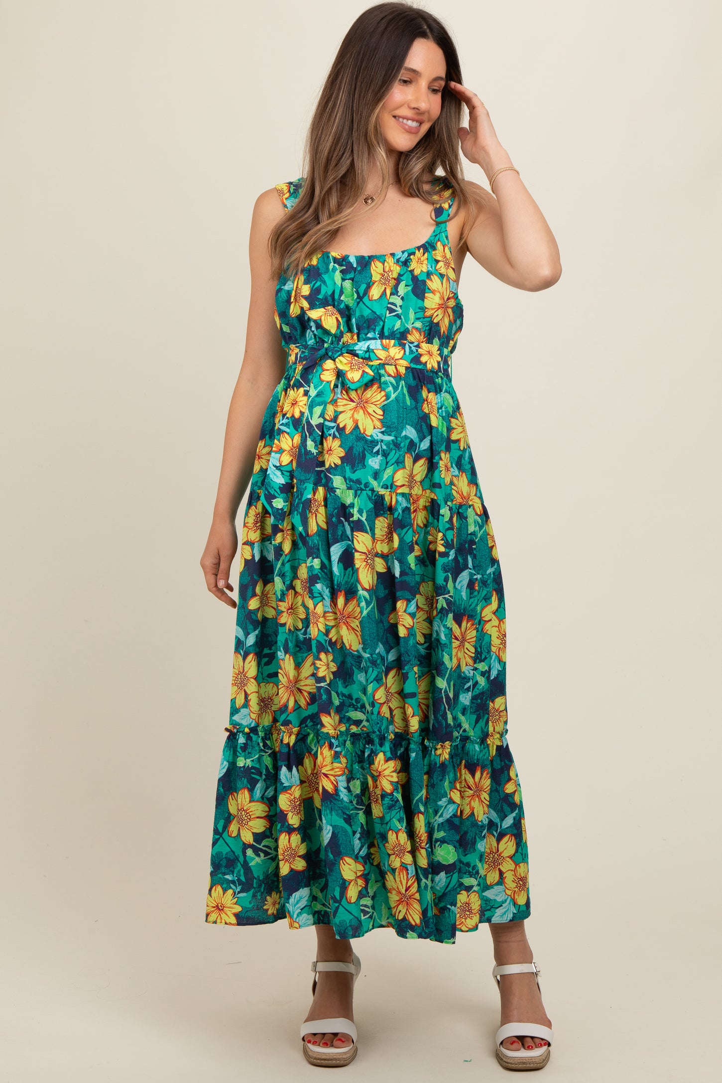 woman wearing a floral print maternity maxi dress with a fitted bodice and tiered skirt, showcasing a visible baby bump