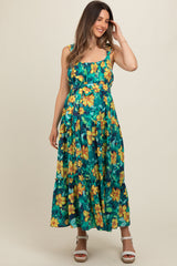 woman wearing a floral print maternity maxi dress with a fitted bodice and tiered skirt, showcasing a visible baby bump