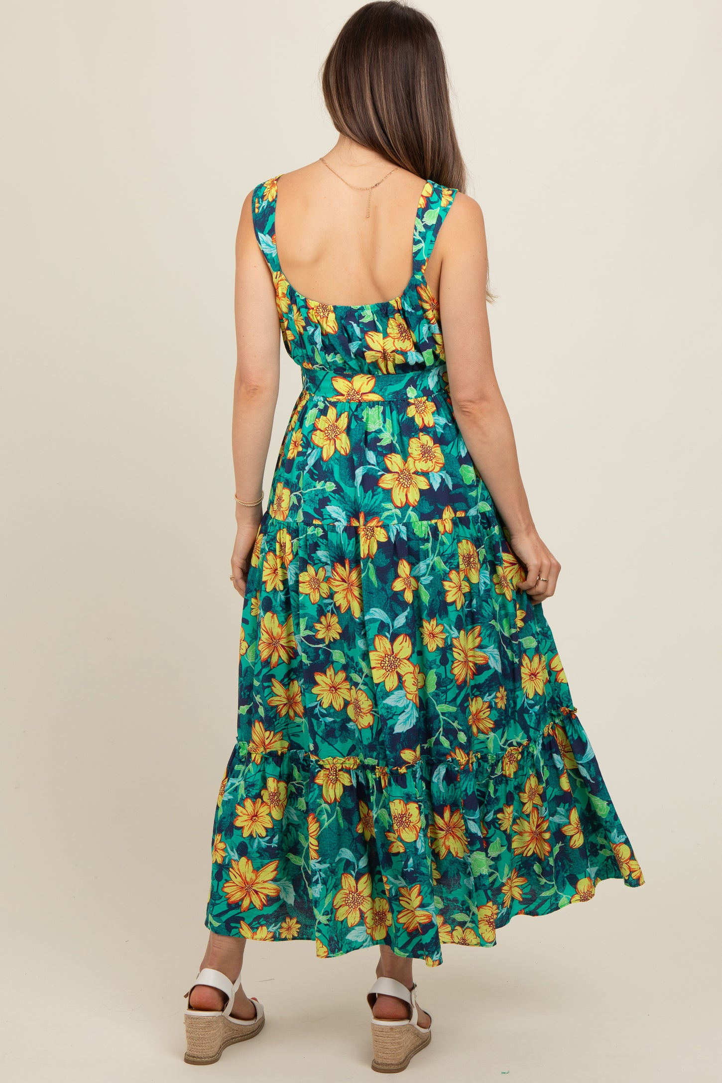 woman wearing a floral maternity maxi dress with yellow and green flowers, showing a back view