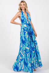 woman wearing a halter neck maxi dress in blue abstract print with a cinched waist and flowy skirt