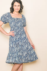 woman wearing a navy blue floral print midi dress with puff sleeves and a square neckline