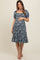 woman wearing a blue floral maternity dress with short puff sleeves and a tiered skirt, highlighting her baby bump