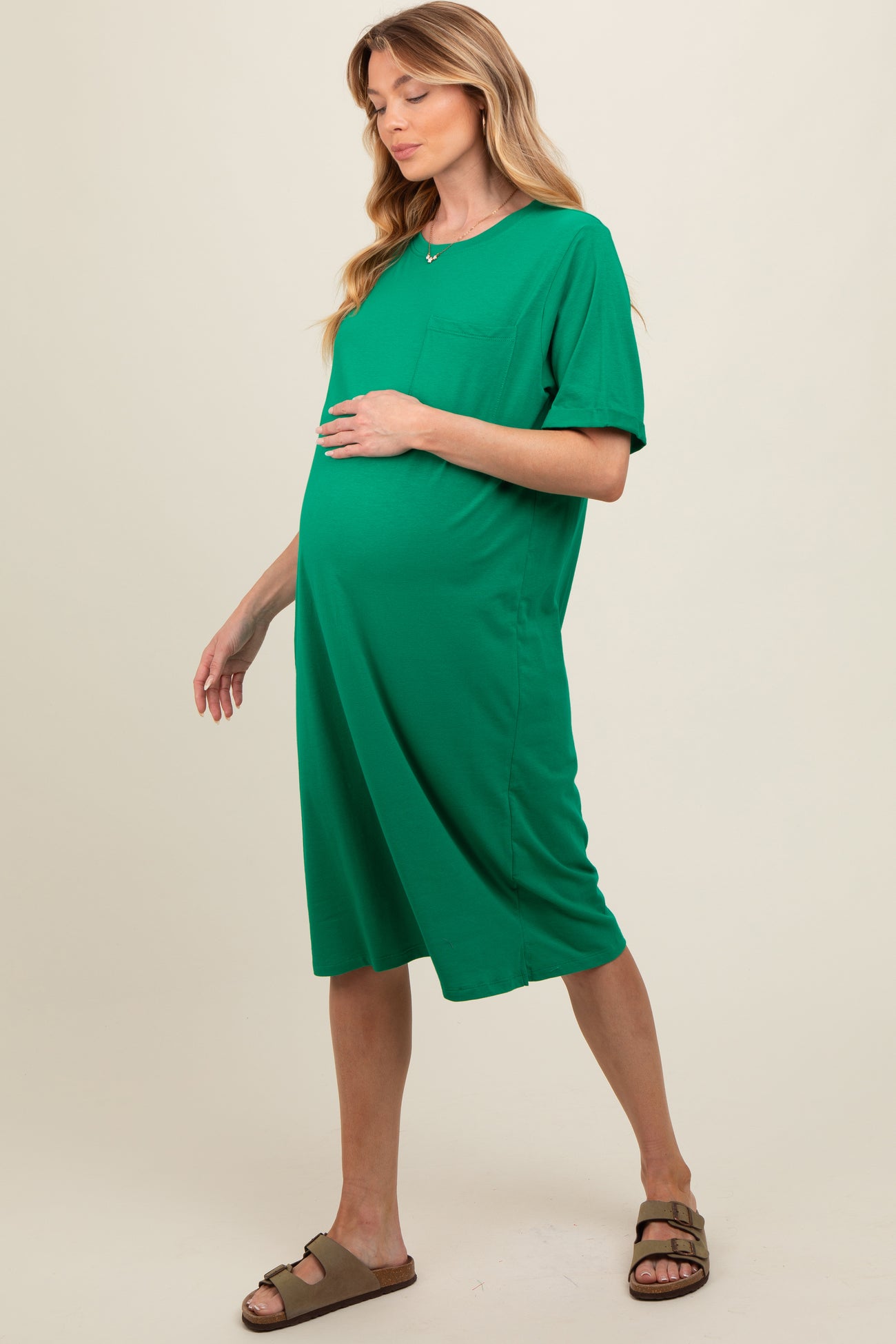 woman wearing a green short sleeve maternity dress with a pocket and a visible baby bump