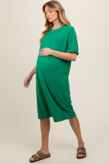 woman wearing a green short sleeve maternity dress with a pocket and a visible baby bump