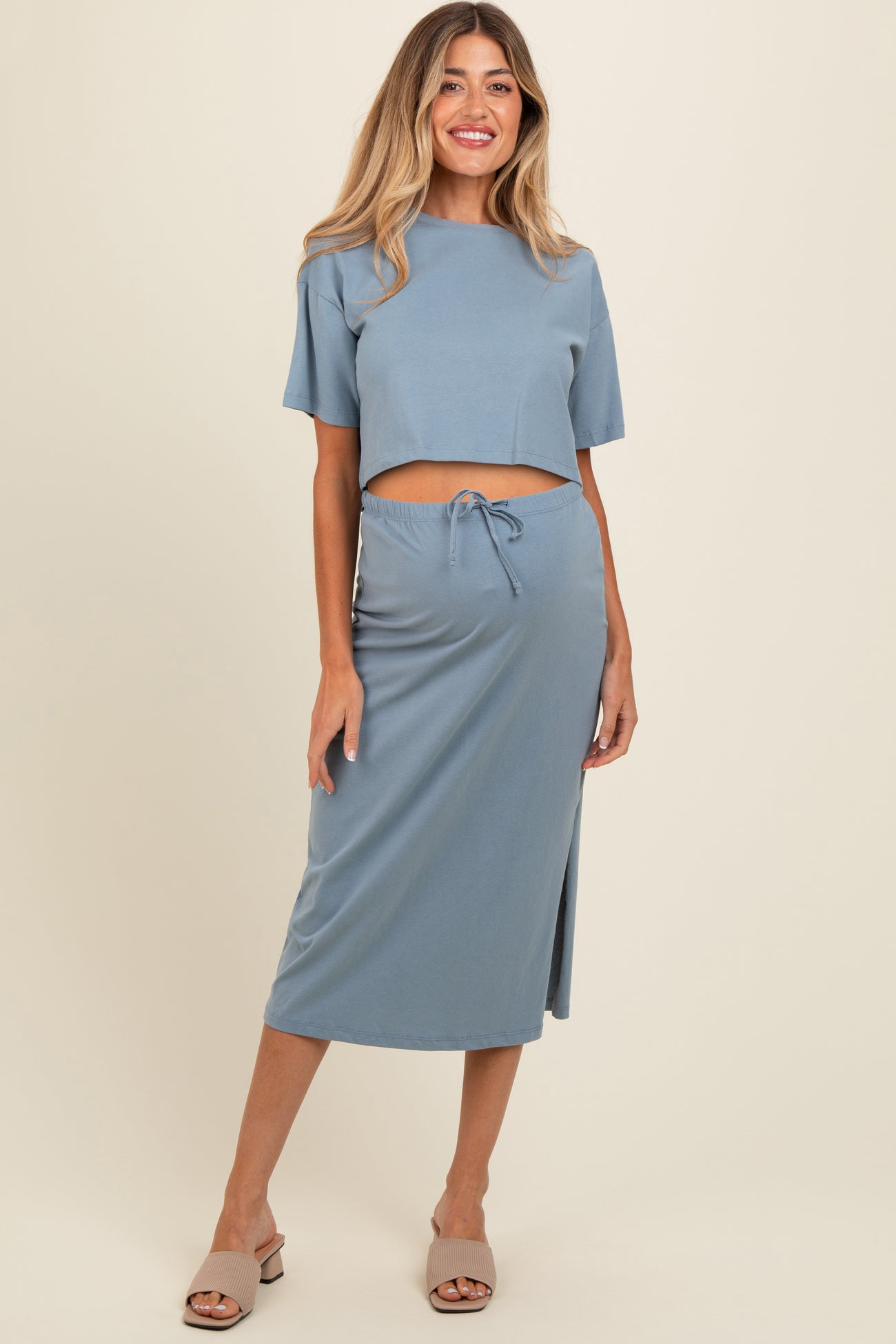 woman wearing a blue maternity crop top and matching midi skirt with a drawstring waist and side slit