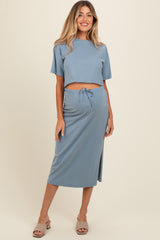woman wearing a blue maternity crop top and matching midi skirt with a drawstring waist and side slit