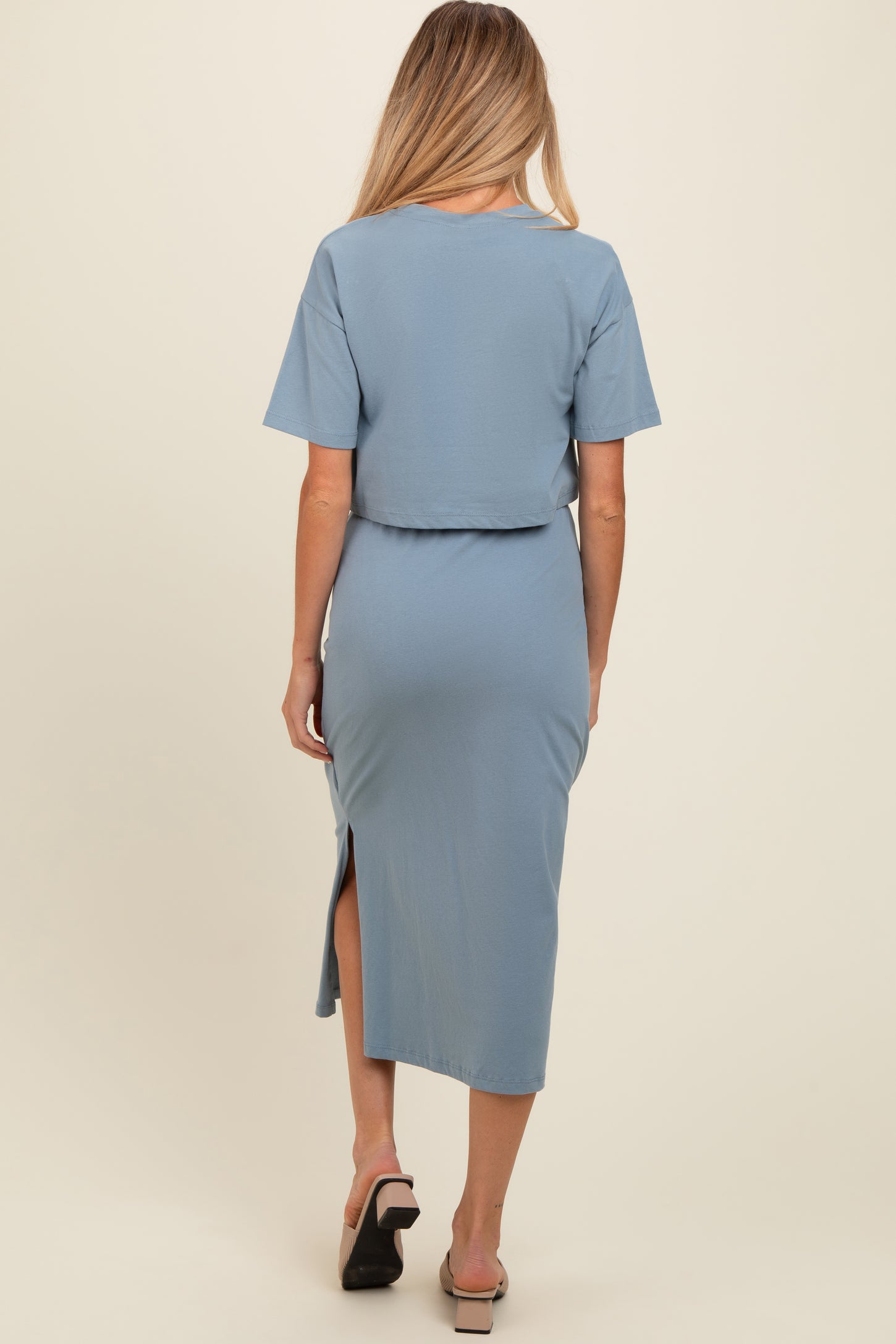 woman wearing a light blue maternity dress with short sleeves and a side slit, showing a baby bump from the back