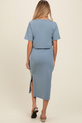 woman wearing a light blue maternity dress with short sleeves and a side slit, showing a baby bump from the back