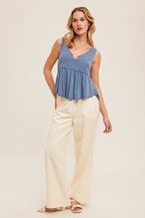 woman wearing a denim blue peplum tank top and cream wide-leg pants