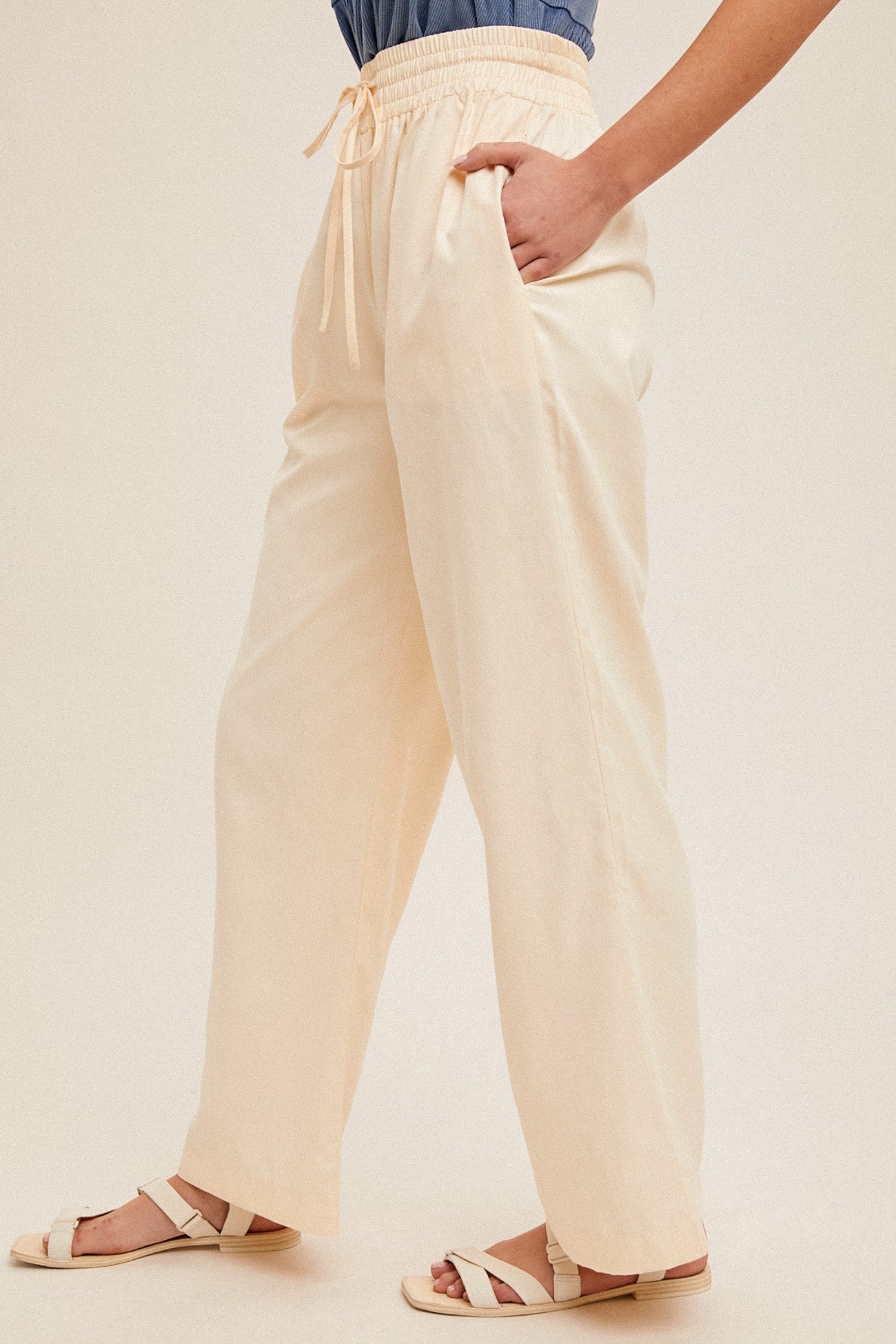 woman wearing cream wide-leg pants with elastic waistband and side pockets, paired with a denim top