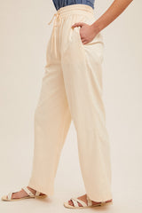 woman wearing cream wide-leg pants with elastic waistband and side pockets, paired with a denim top