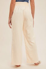 woman wearing back view of light cream wide-leg pants with an elastic waistband