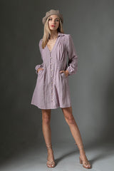woman wearing a light lavender button-up shirt dress with puff sleeves and pockets, styled with a beret and strappy heels