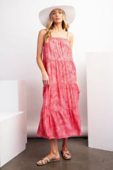 woman wearing a pink tropical print maxi dress with a tiered design and a wide-brimmed hat