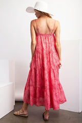 woman wearing a pink tiered maxi dress with a tropical pattern and spaghetti straps, showing the back view