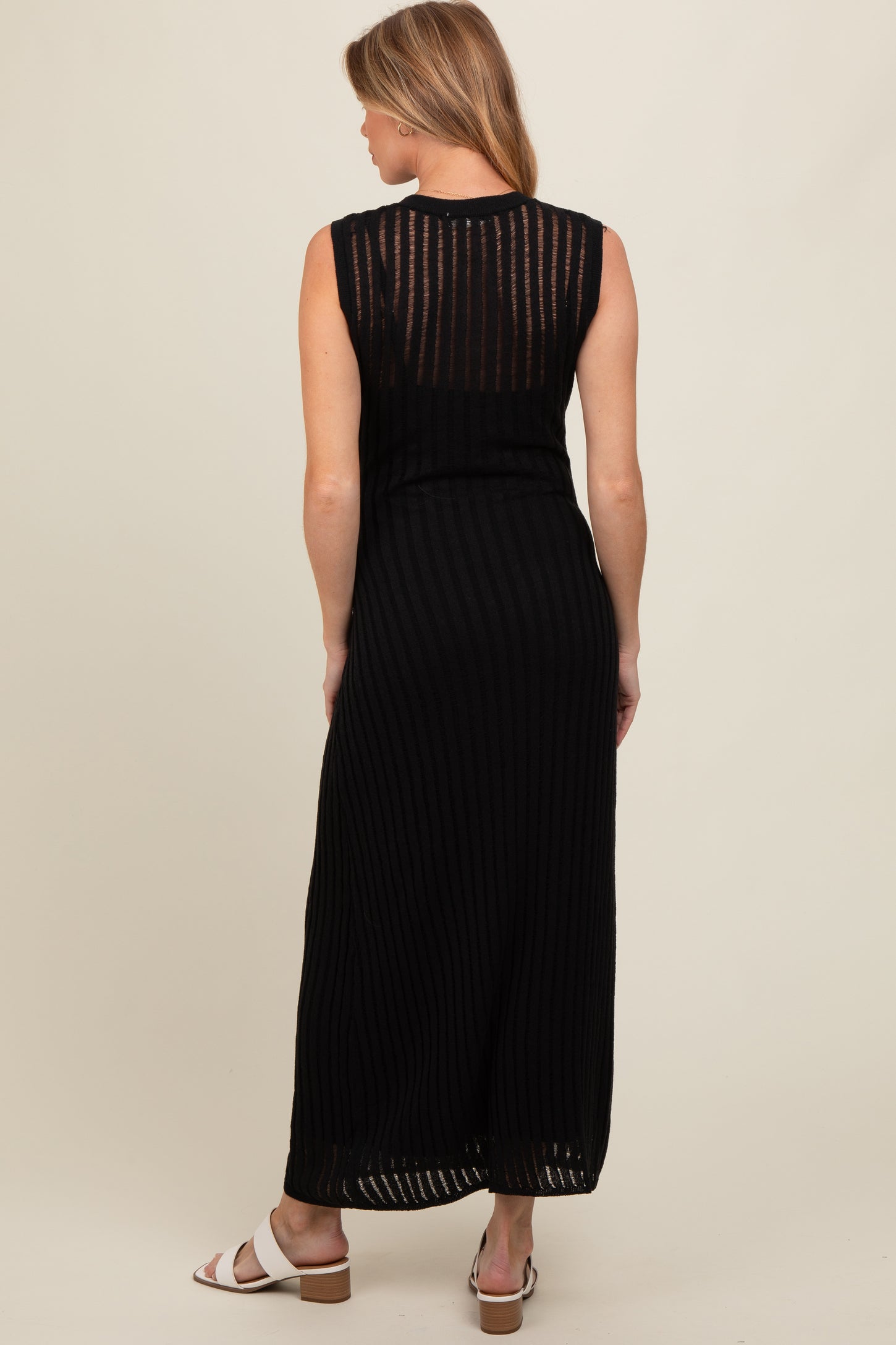 woman wearing a black sleeveless maternity maxi dress with vertical stripes, showing her back