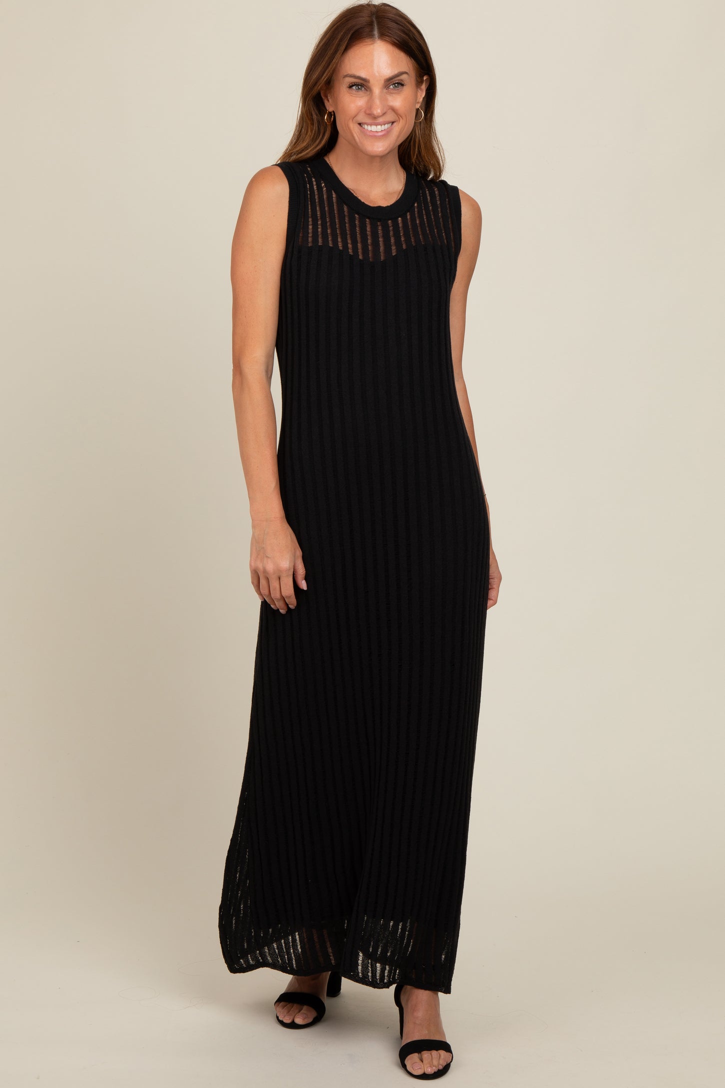 woman wearing a black ribbed maxi dress with a sheer striped neckline and side slits