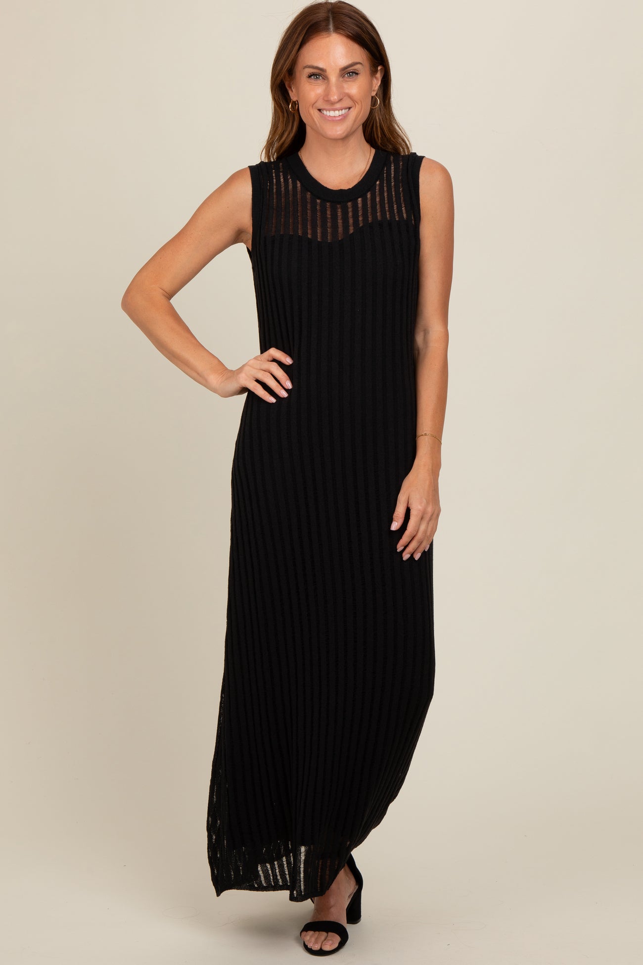 woman wearing a black sleeveless maxi dress with vertical stripes and a sheer neckline detail