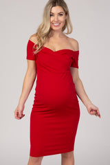 woman wearing a red off-the-shoulder maternity dress that highlights her baby bump