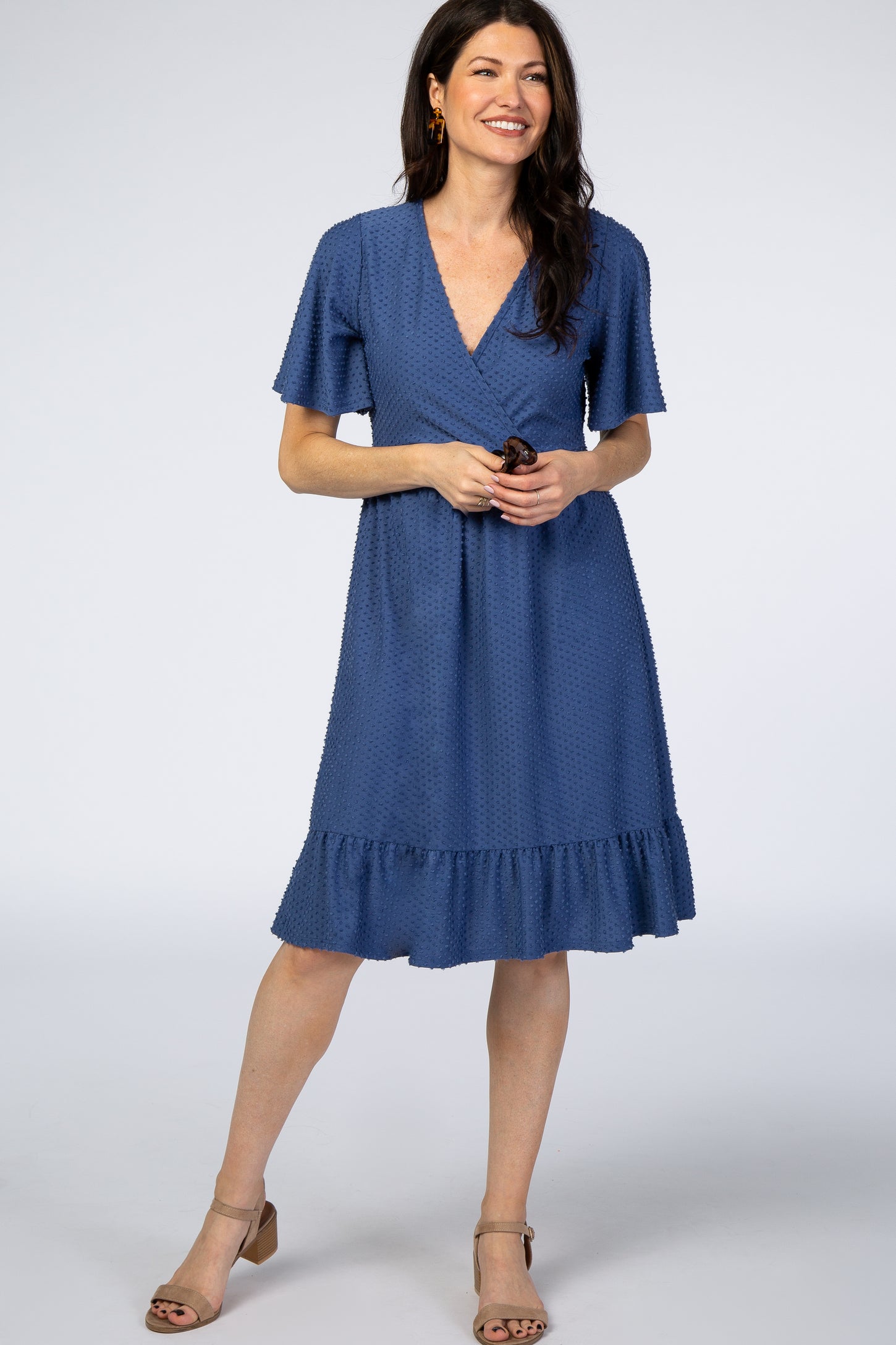 woman wearing a blue dotted wrap dress with short sleeves and a ruffled hem
