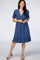 woman wearing a blue dotted wrap dress with short sleeves and a ruffled hem